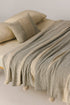 Korfu linen coverlet with pompom trim detail in black, draped over bed