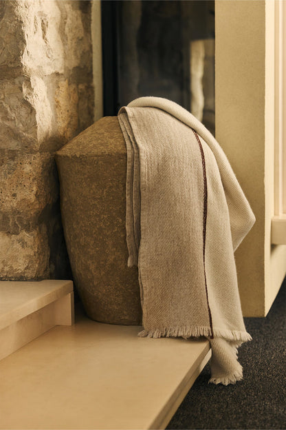Anvers wool throw with two-tone design and fringed edges on armchair